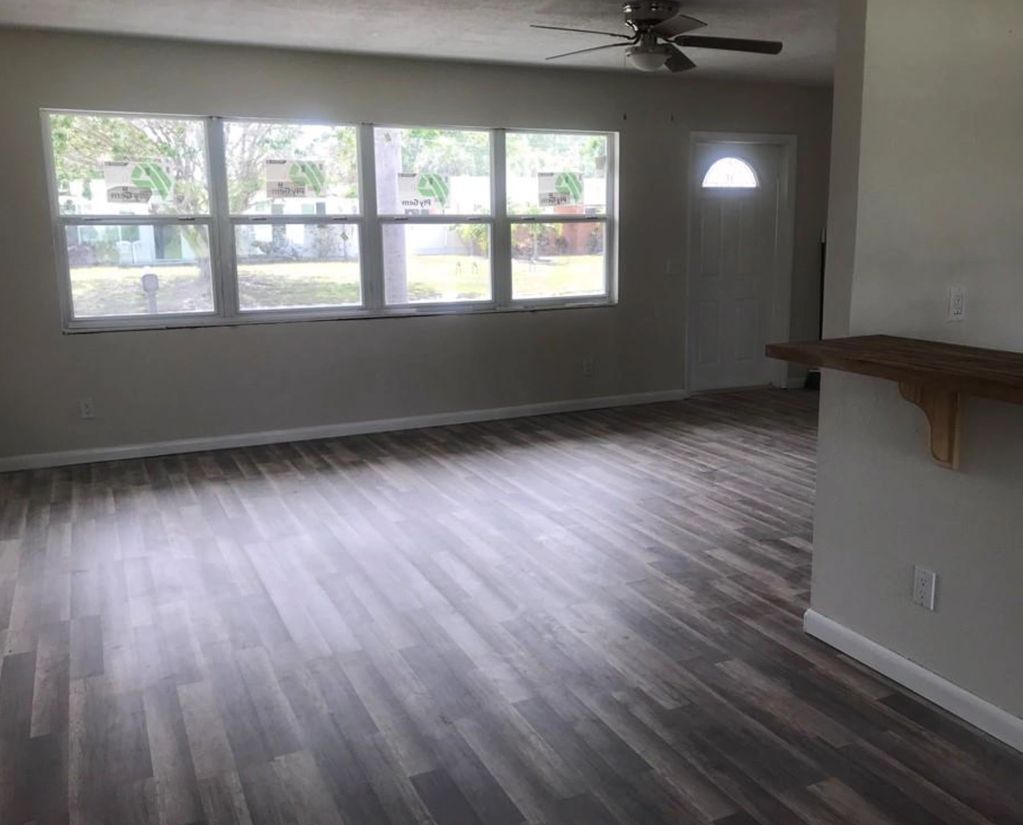 This living room transformed with new flooring, fresh paint, new ceiling fan and new baseboards.