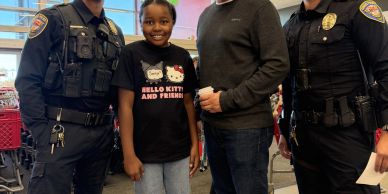 Two police officers and two civilians smiling inside a store.