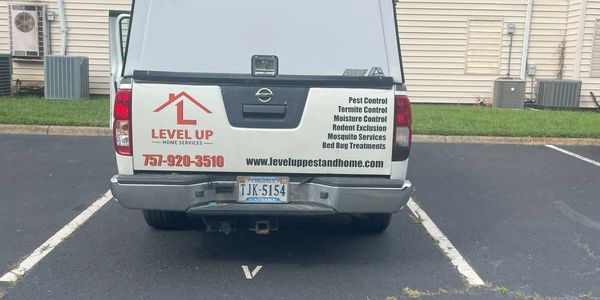 Back of a pest control service vehicle parked in a lot.