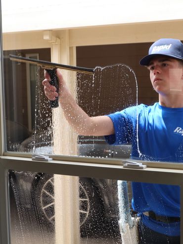 A man cleaning a window with a squeegee.
