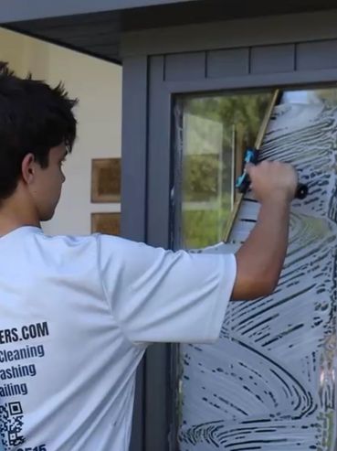 Person cleaning a glass door with a squeegee.