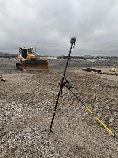 Surveying equipment set up on a construction site with a bulldozer in the background.