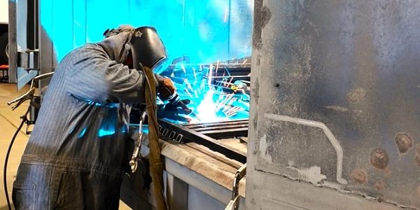 Worker welding metal with sparks flying.