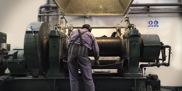 A worker operates heavy industrial machinery in a factory setting.