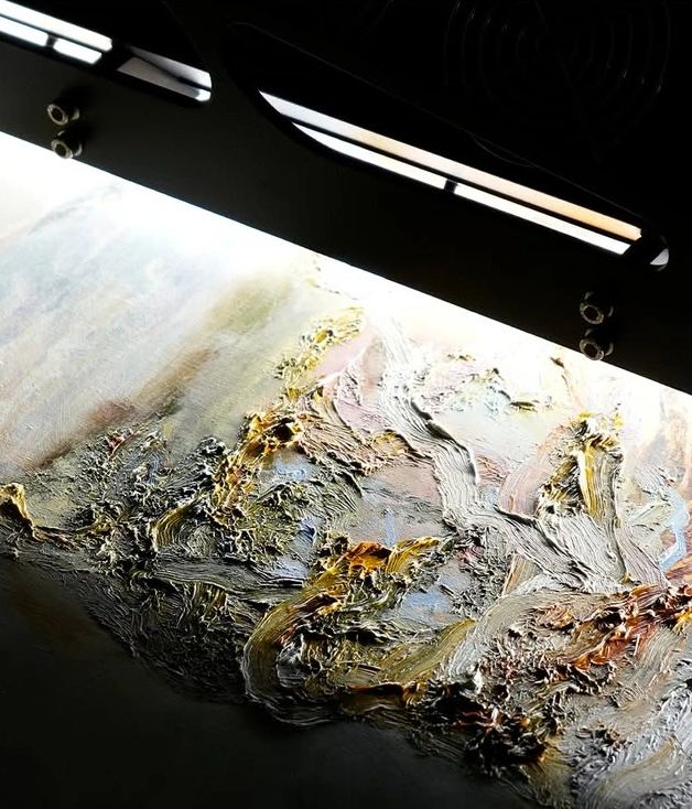Close-up of textured abstract painting with light illuminating it.