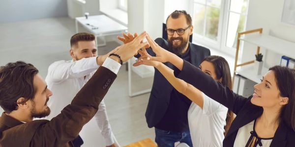 A group of five colleagues doing a team high-five in an office.