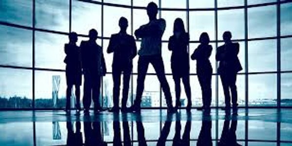 Silhouetted business team standing confidently in front of large window.