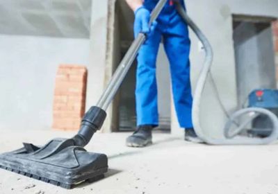 A person uses a vacuum to clean the floor.