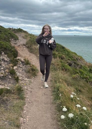 Person walking on coastal path by the sea.