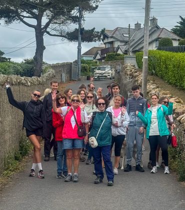 Group of people walking on a country road waving at the camera.
