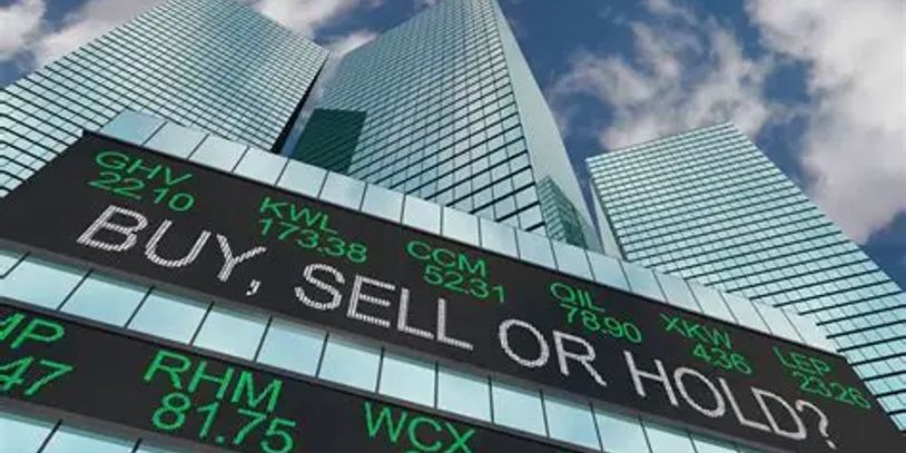 Stock market board displaying "BUY, SELL OR HOLD?" on a city skyscraper.