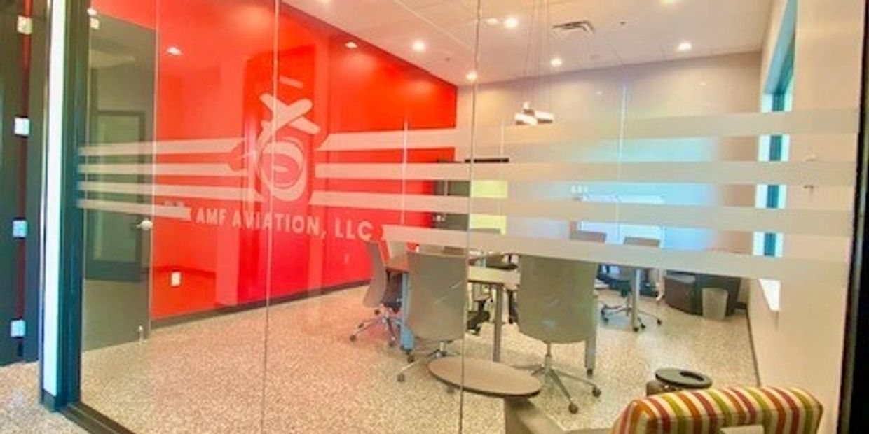 Modern office meeting room with glass walls and red accent wall.