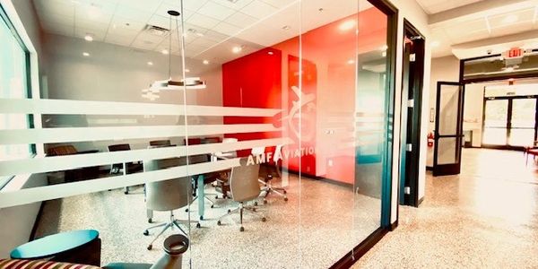 Modern office conference room with glass walls and red accent wall.