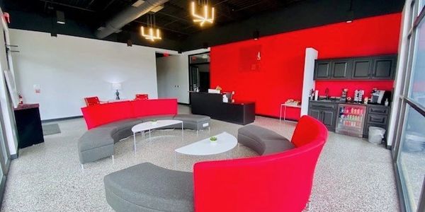 Modern waiting area with red and gray curved seating and vibrant red accent wall.
