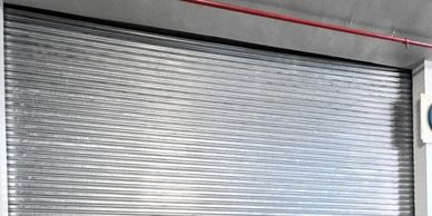Closed metallic rolling shutter door in a concrete building.