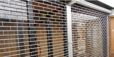 Metal security gate partially closed in front of a storage area.