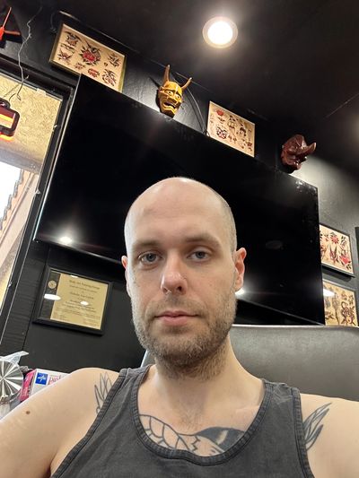 Man with tattoos taking a selfie indoors.