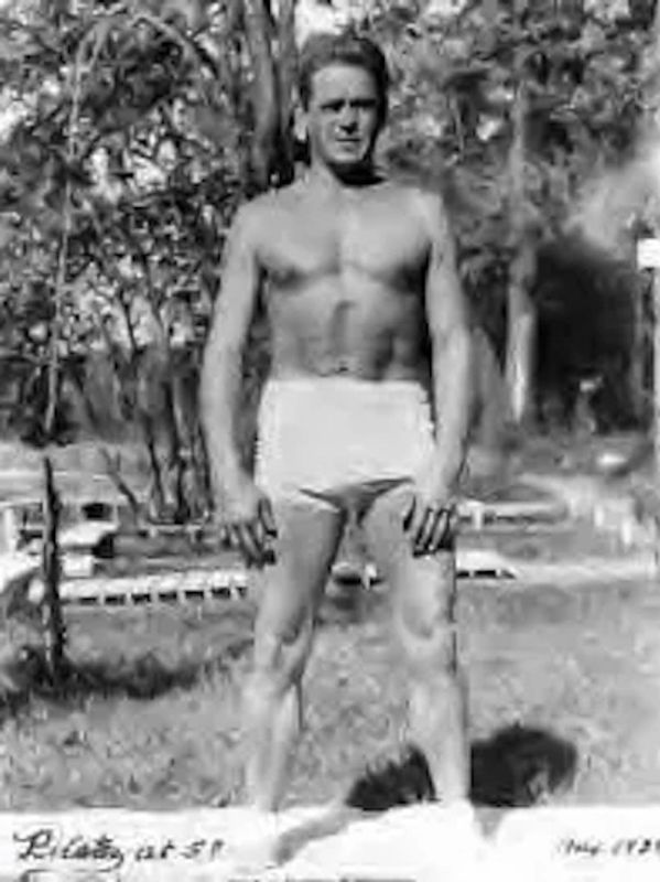 Black and white photo of a man in swim trunks outdoors.