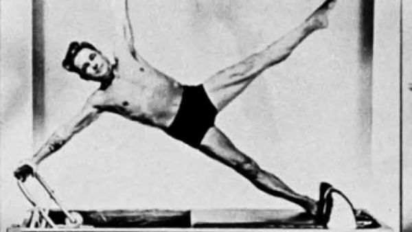 Man performing an exercise on a pilates reformer machine.