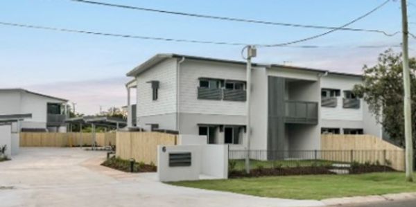 Modern two-story white house with a fence and driveway.