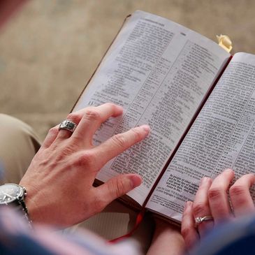 Person reading a book with two hands visible.
