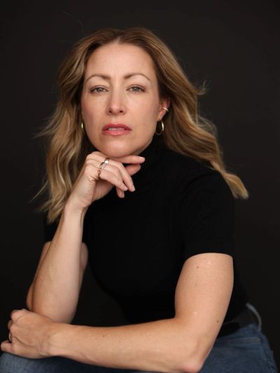Woman with blonde hair in a black top posing thoughtfully.