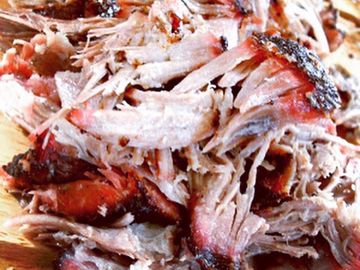 Close-up of shredded smoked pulled pork with a smoky bark.
