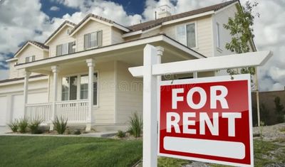 A house with a for rent sign in front on a sunny, but cloudy afternoon.