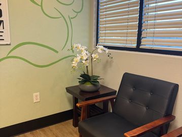Cozy corner with a chair, table, and flower pot.