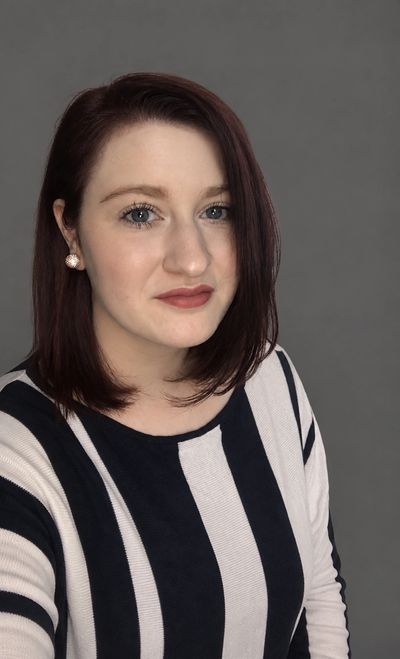 Woman with red hair wearing a striped black and white top.
