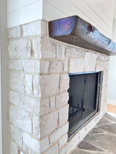 Stone fireplace with a rustic wooden mantle and protective screen.