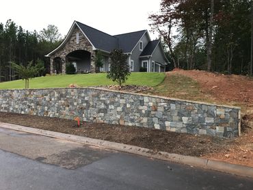 Modern house with stone accents and a tiled retaining wall.