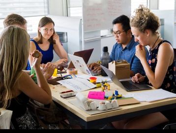 Group of young adults collaborating on laptops in a bright office space.