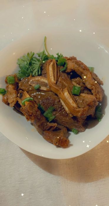 meat with greens on white plate on table