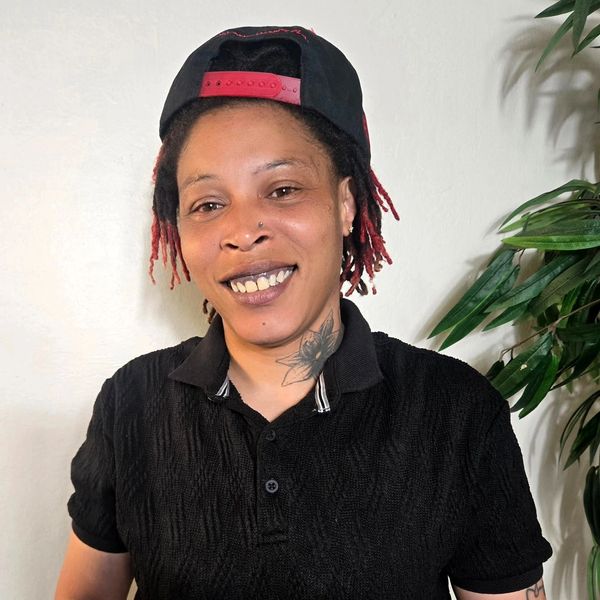 Person smiling wearing a black shirt and backward cap.