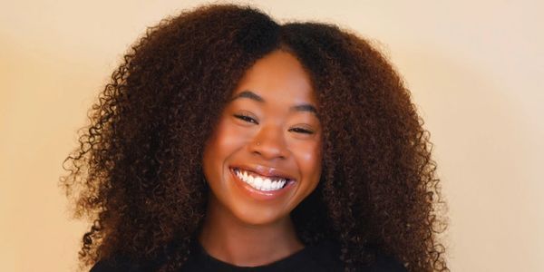 Young woman with curly hair smiling brightly.