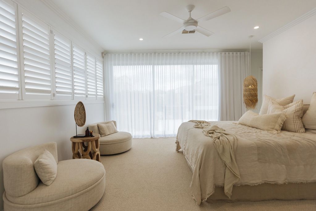 Elegant beige bedroom with natural light and cozy furniture.