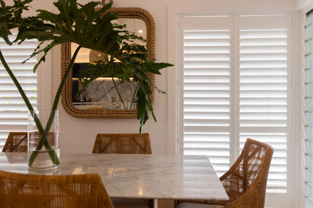 Dining area with rattan chairs and a marble table.