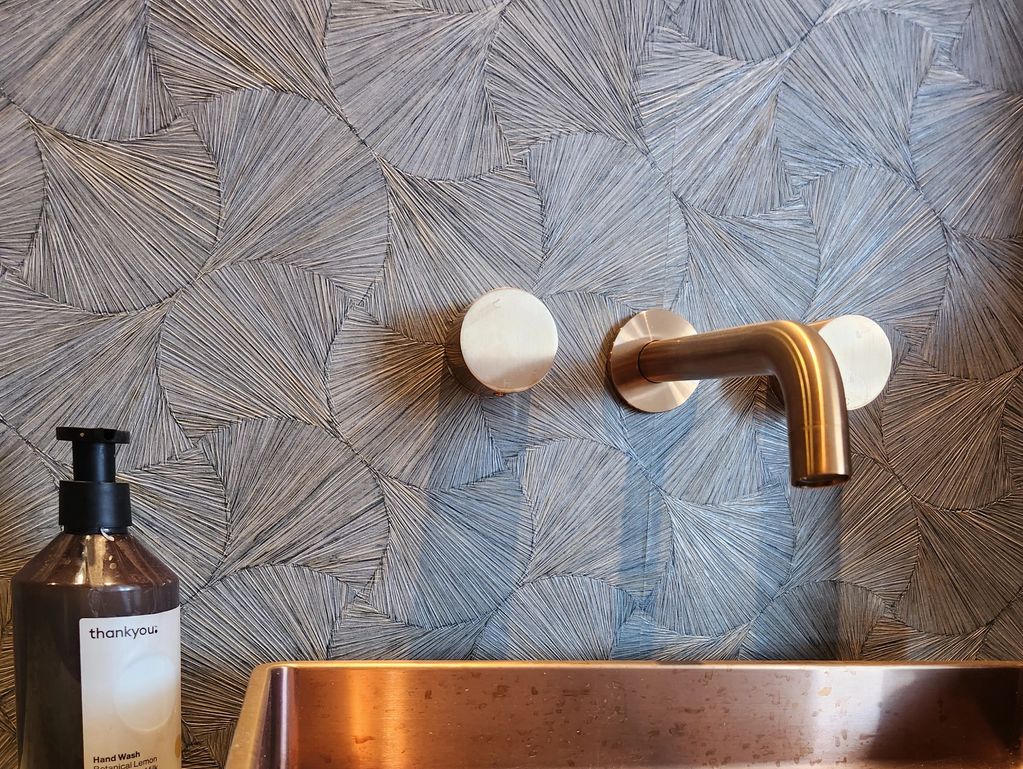 Modern sink setup with textured wall and hand wash.