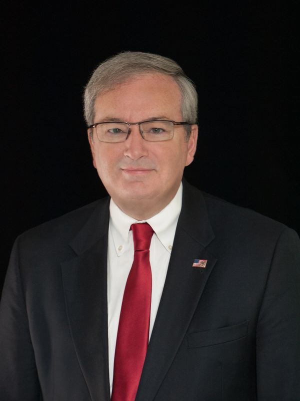 Professional man in suit and red tie with American flag pin.