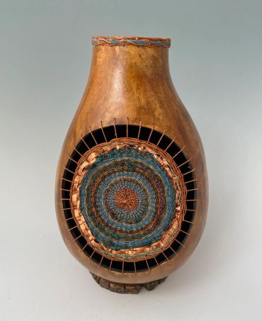 Decorative woven and wooden vase with intricate circular pattern.