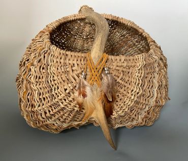 Handwoven basket with decorative feathers and tail.