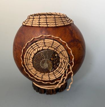 Decorative round pot with woven spiral design and fossil inside.