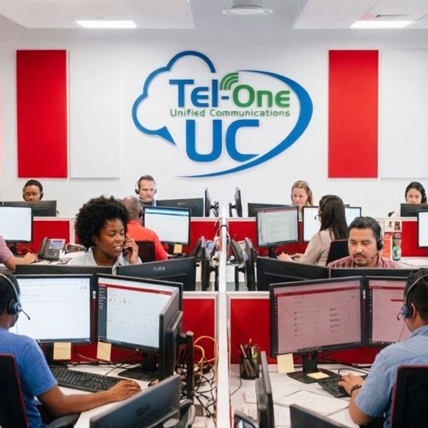 Busy call center with employees working on computers and phones under Tel-One UC branding.