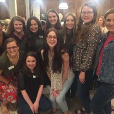 Group of smiling women posing indoors.
