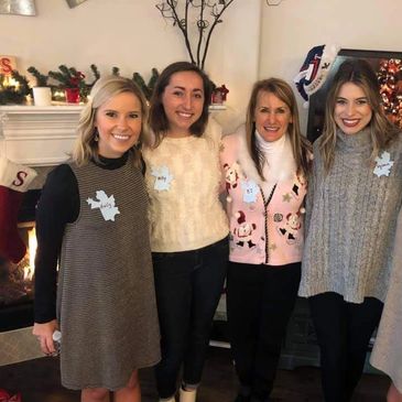 Four women posing together indoors at a holiday gathering.