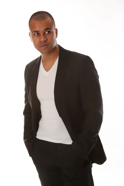 Man in black suit with white shirt looking to the side.