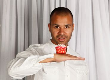 Man balancing a red cupcake on his hand.