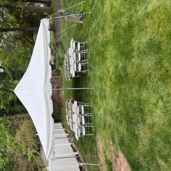 White tent with tables and chairs set up on a green lawn.