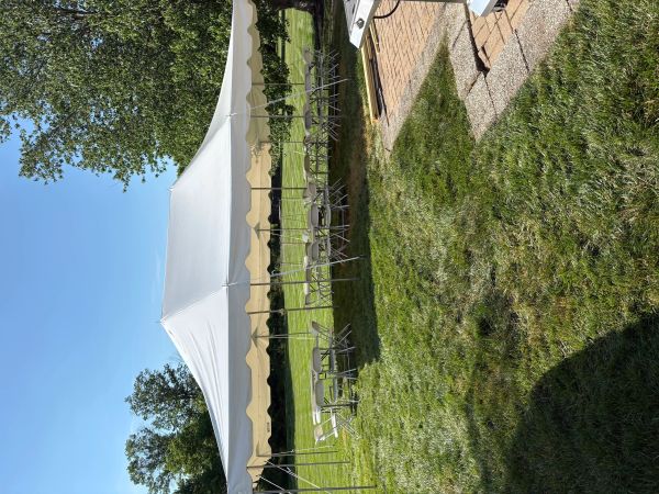 White canopy tent with chairs set up on a sunny green lawn.